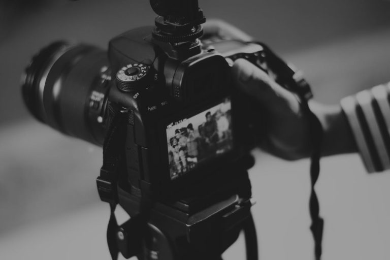 Grayscale Photography of Person Holding Black Dslr Camera